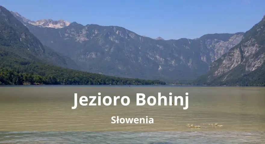 Spokojne jezioro Bohinj w Słowenii otoczone zielonymi wzgórzami i skalistymi górami.
