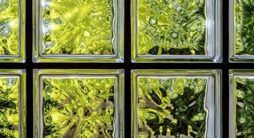 Fenster mit Glasbausteinen, die grünes Laub und Bäume durchscheinen lassen. Ideal, um alte Fenster durch moderne Glasbausteine zu ersetzen.