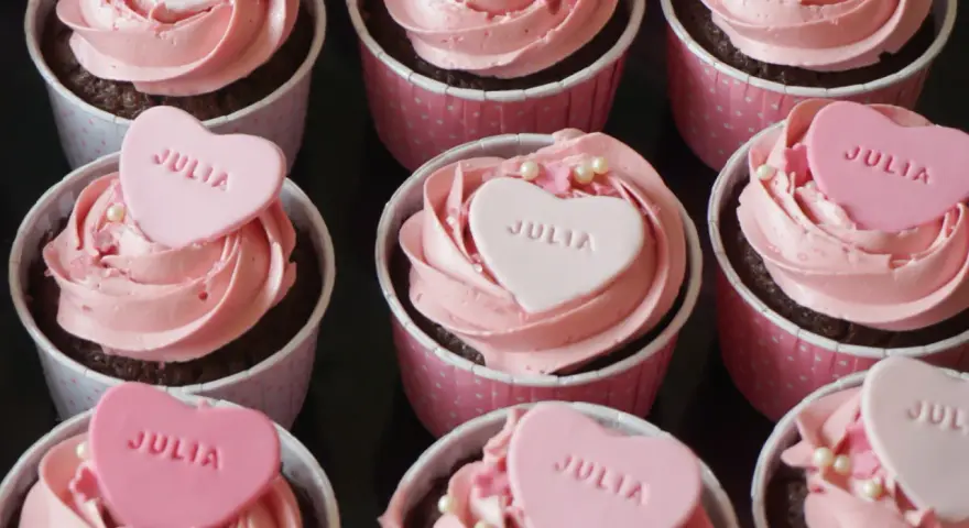 Rosa cupcakes med hjärtformade dekorationer med texten "JULIA". Perfekt för en speciell Julia!