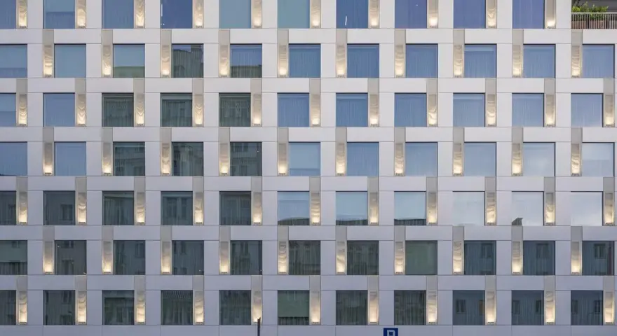 Nowoczesny hotel Puro Warszawa z licznymi oknami i pionowymi podświetlanymi elementami fasady.
