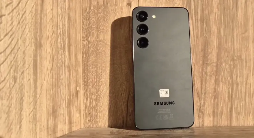 Szary Samsung S23 z trzema obiektywami aparatu na drewnianym tle. Długo działająca bateria pozwoli Ci cieszyć się nim przez cały dzień.