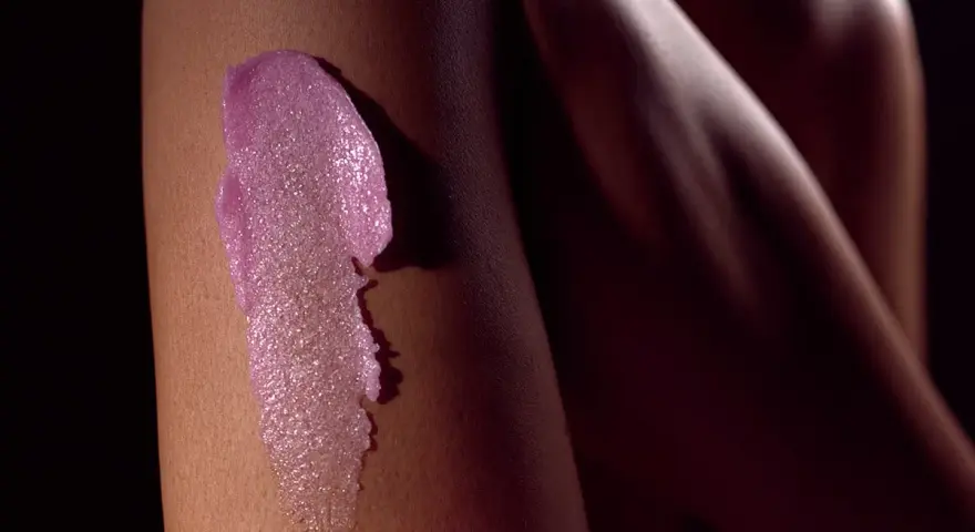 Różowy peeling na skórze nogi. Zastanawiasz się, **najpierw peeling czy golenie**? Ten zabieg przygotuje skórę do gładkiego golenia.