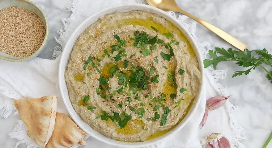 Crema de berenjena asada con aceite de oliva, perejil y semillas de sésamo, servida con pan de pita.
