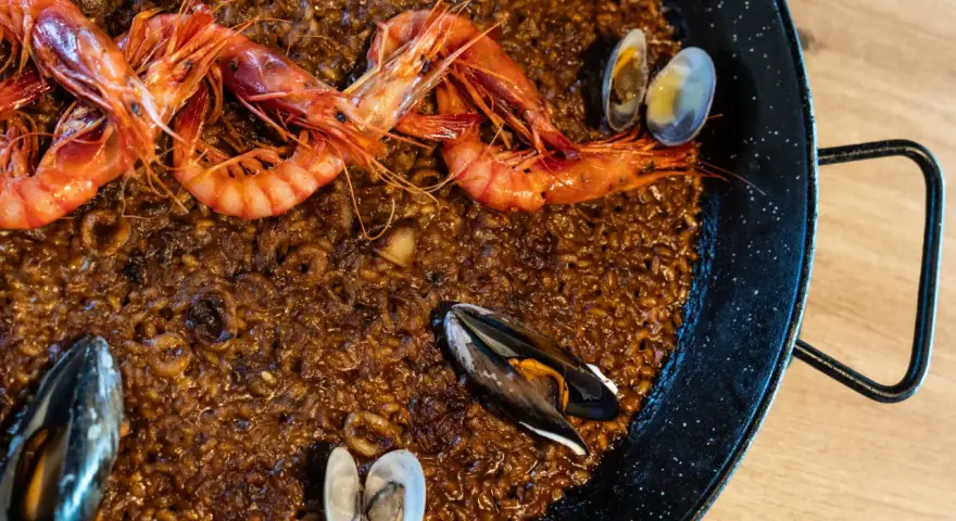 Paella de marisco con gambas rojas, mejillones y almejas sobre arroz dorado.