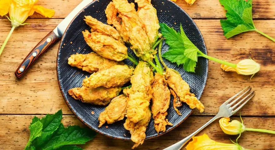 Fiori di zucca in friggitrice ad aria, dorati e croccanti, pronti per essere gustati.