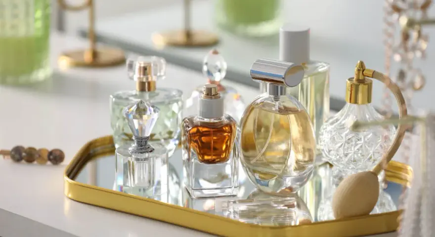Kolekcja flakonów z płynną esencją perfum, w tym jeden z atomizerem, na złotym lustrzanym tacy.