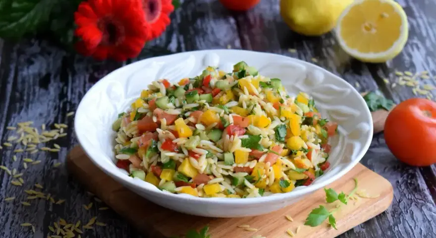 Kolorowa sałatka z makaronem orzo, pomidorami, ogórkiem i papryką. Idealna na letni obiad.