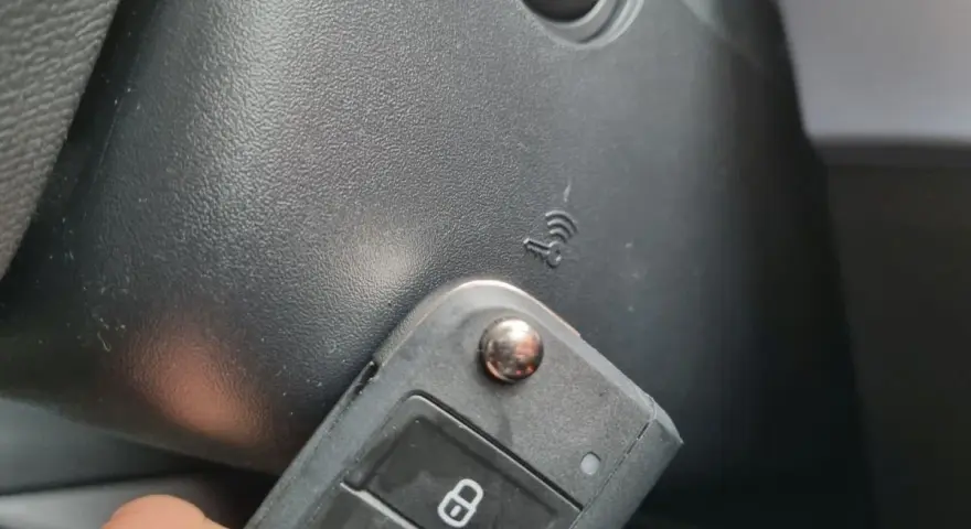 Kluczyk samochodowy z funkcją keyless go w pobliżu przycisku start.