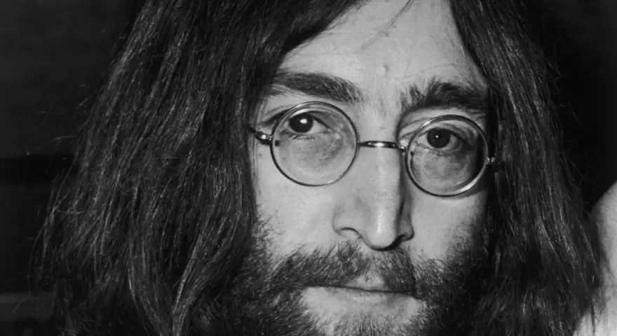 Nahaufnahme von John Lennon III. mit runden Brillengläsern und Bart.