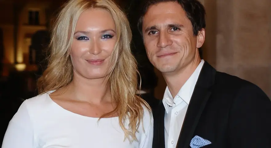 Uśmiechnięta para, być może rodzice Sambora Czarnoty, pozuje do zdjęcia. Kobieta ma blond włosy i białą sukienkę, mężczyzna czarny garnitur.