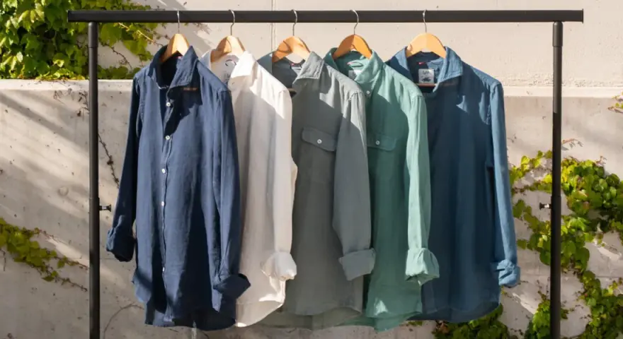 Cinco camisas de lino de colores cuelgan en una percha. El lino, de donde viene el lino, es una fibra natural.