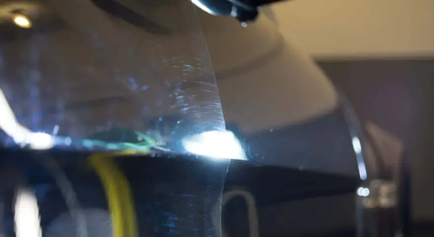 Widoczne rysy na lakierze ciemnego auta, które można usunąć, ucząc się jak wypolerować auto.