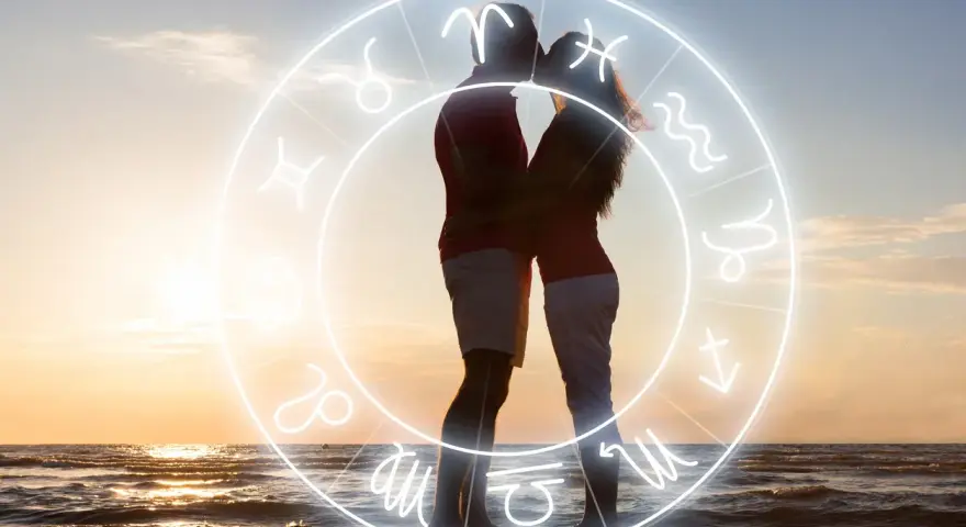 Para Skorpiona: para zakochanych na plaży w zachodzącym słońcu, otoczona znakiem zodiaku.