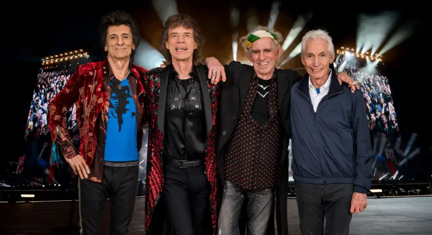 Członkowie The Rolling Stones pozują przed tłumem na jednym z ich niezapomnianych **koncertów**.
