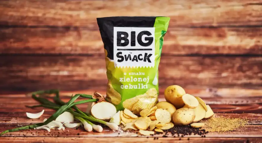 Reklamowa fotografia chipsów Big Snack o smaku zielonej cebulki, z ziemniakami i cebulką.