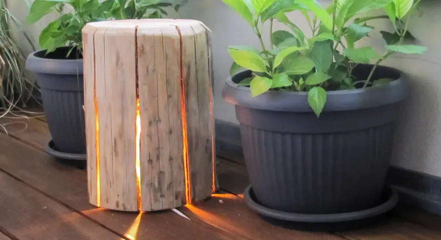 Un tronco di legno con fessure illuminate, un'idea creativa per come costruire una fioriera in legno.