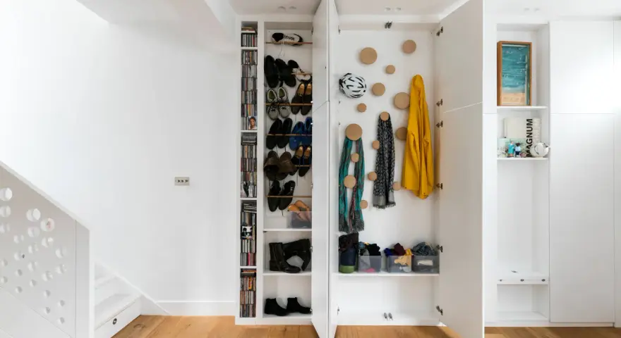 Moderne Garderobe Ideen: Offene Fächer mit Schuhen, Jacken und Schals. Ein Fahrradhelm hängt an der Wand.