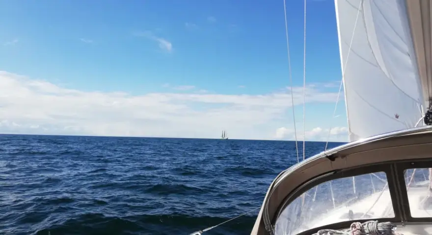 Segeln in Deutschland: Ein Segelboot gleitet über das Meer, im Hintergrund ein weiterer Segler unter blauem Himmel.