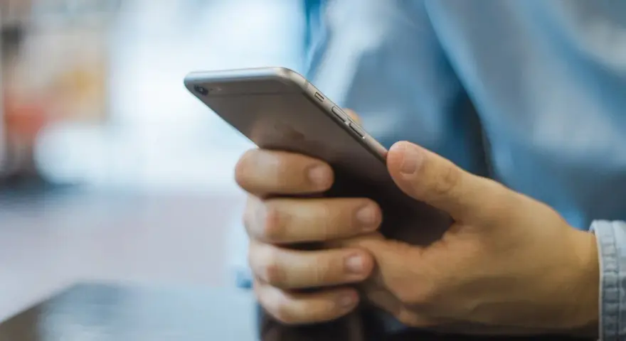 Dłonie trzymające smartfon, szukające inspiracji, jak zacząć rozmowę na Badoo.