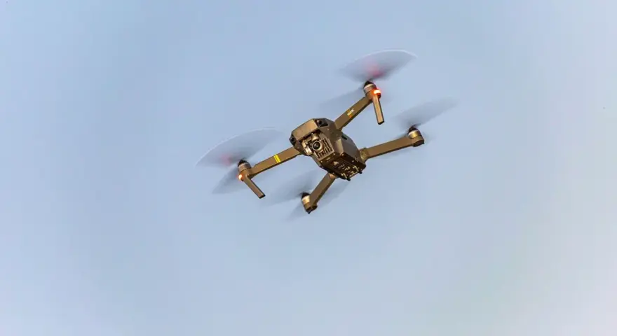 A drone flies in the sky, a reminder to check Maine drone laws before takeoff.