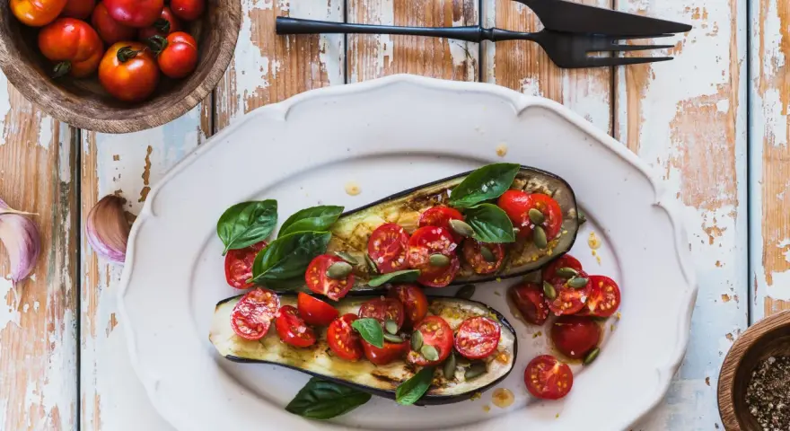 Melanzane ripiene vegetariane con pomodorini, basilico e semi di zucca, un piatto colorato e saporito.