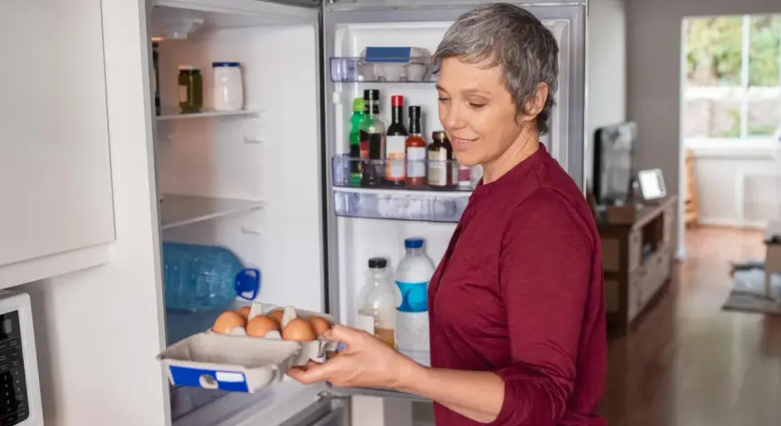 Frau holt Eier aus dem Kühlschrank. Nach einer Darmspiegelung ist leichte Kost wie Eier oft das erste Essen.