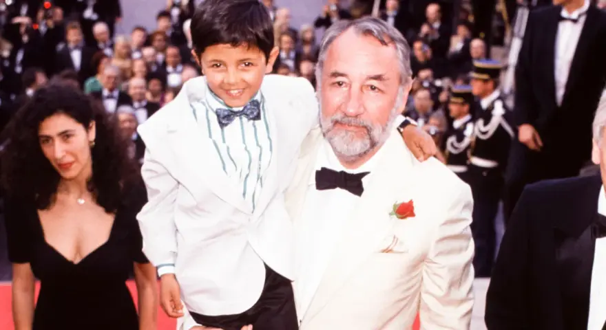 Un bambino sorridente, protagonista di "Nuovo Cinema Paradiso", abbracciato da un uomo con una rosa all'occhiello.