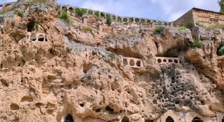 Antigua ciudad excavada en roca, con arcos y ventanas en las cuevas. Un lugar histórico que parece una cascada de piedra.