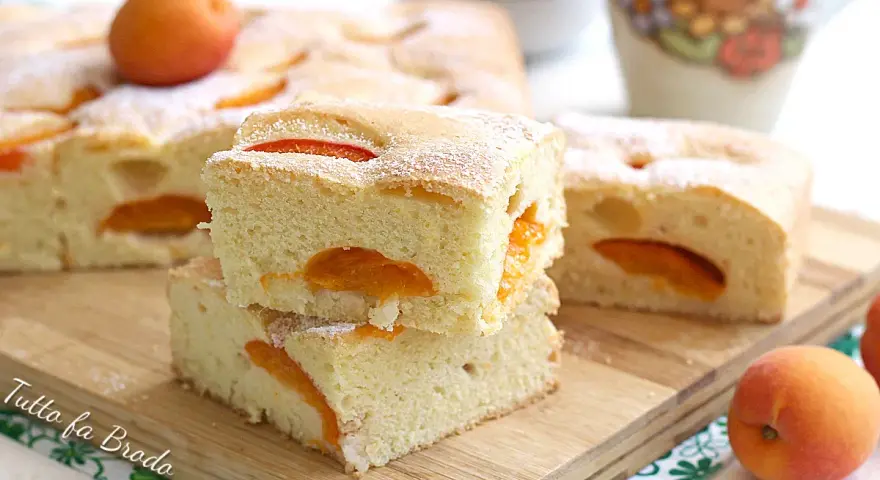 Fette di torta alle albicocche cremosa, soffice e profumata, con albicocche fresche e zucchero a velo.