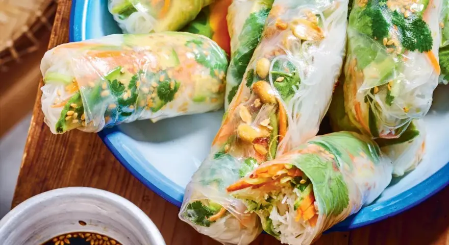 Rouleaux de printemps frais et colorés, parfaits pour une recette facile. On y voit des vermicelles de riz, des légumes croquants et des cacahuètes.