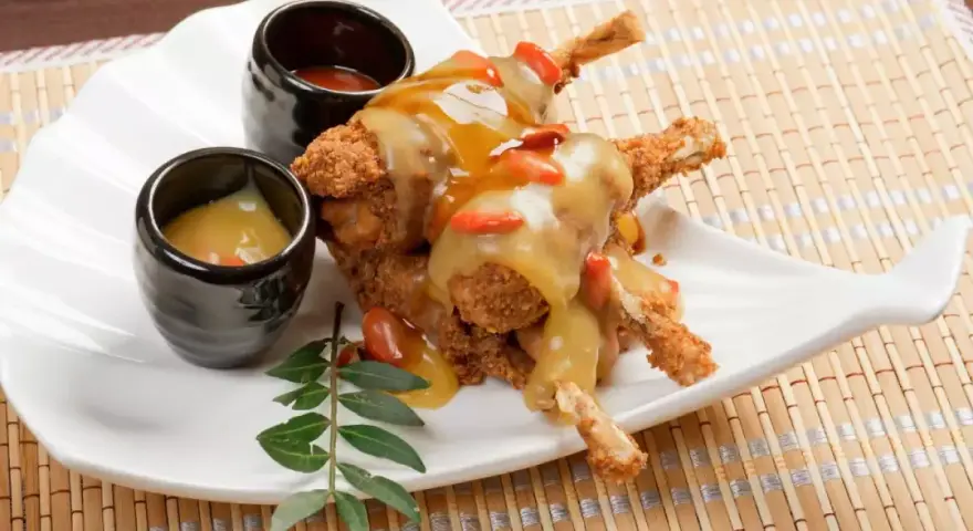 Ancas de rana crujientes con salsa dorada y gominolas rojas, acompañadas de dos salsas. Una deliciosa receta francesa.