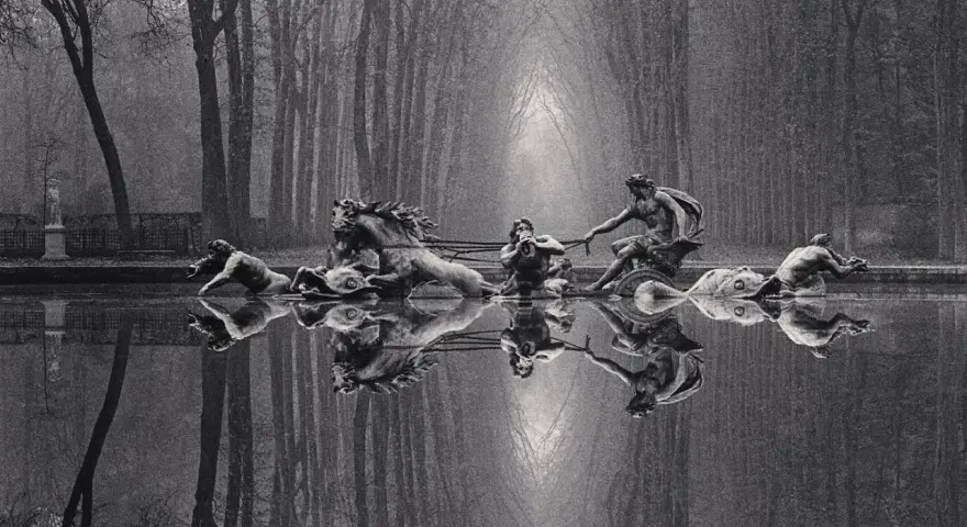 Rzeźby w stawie, koń i ludzie, odbijają się w wodzie. Styl Michael Kenna.