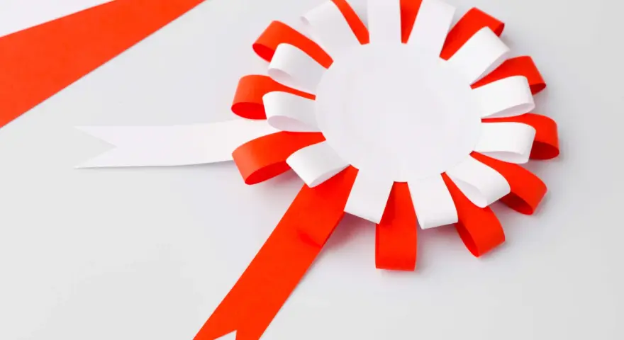 Papierowy kotylion w biało-czerwonych barwach, gotowy do ozdobienia. Idealny szablon do stworzenia patriotycznego akcentu.