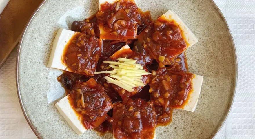 Tofu comida servida en un plato con salsa picante y jengibre rallado.