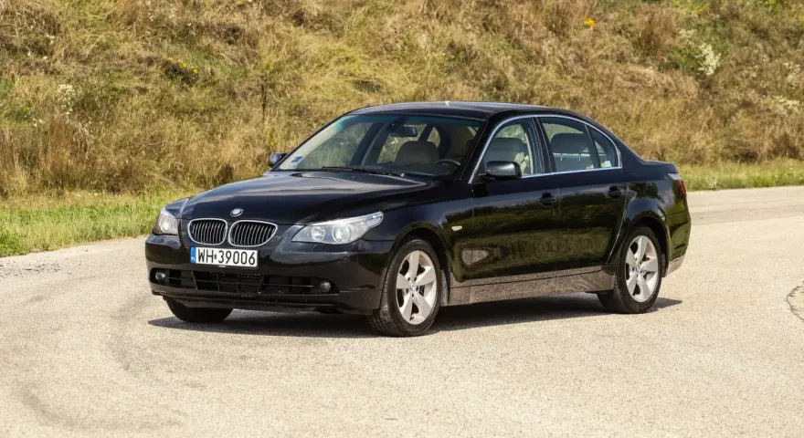 Czarne BMW 535d na tle zielonego wzgórza.