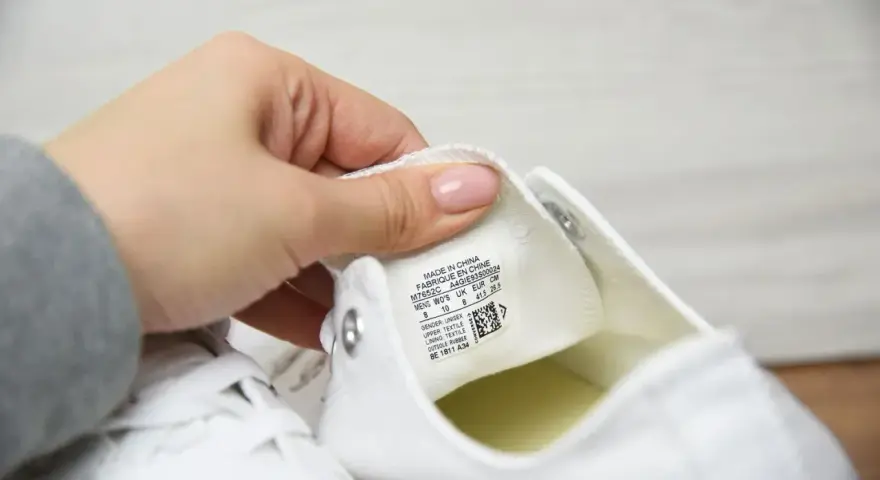 Porównanie converse oryginalne a podróbki. Dłoń pokazuje metkę z rozmiarem na białym bucie.