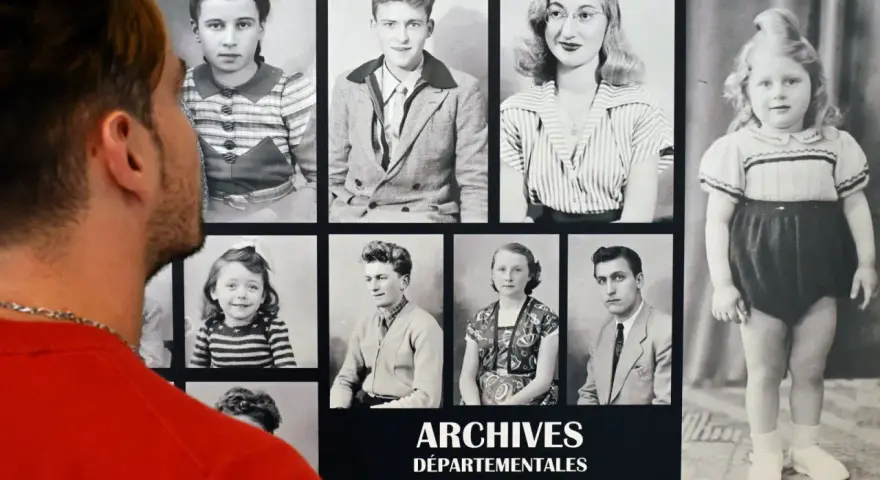 Un homme regarde des archives numérisées : portraits d'enfants et d'adultes d'une autre époque.