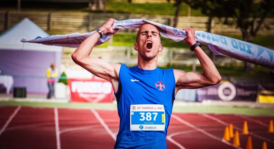 Atleta exhausto, con la boca abierta y una toalla sobre la cabeza, celebra el fin de correr una maratón.