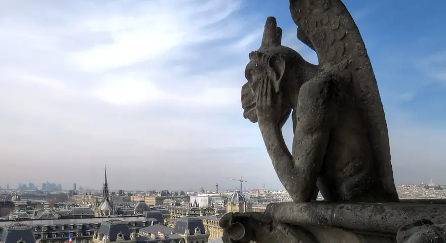 Stryge de Notre Dame, pensif, contemple Paris sous un ciel bleu et nuageux.