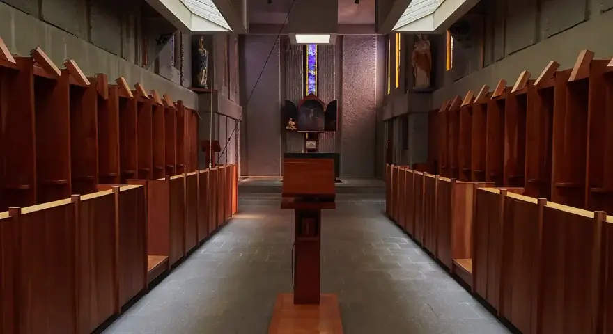 Rows of wooden stalls line the interior of a Carthusian monastery, leading towards an altar.