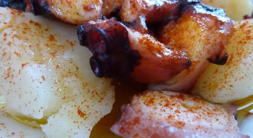 Pulpo con cachelos, un plato gallego tradicional. Tentáculos de pulpo cocidos y trozos de patata, todo espolvoreado con pimentón y aceite de oliva.