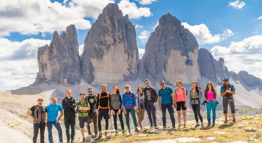 Grupa przyjaciół na tle Tre Cime di Lavaredo podczas niezapomnianego trekkingu w Dolomitach.
