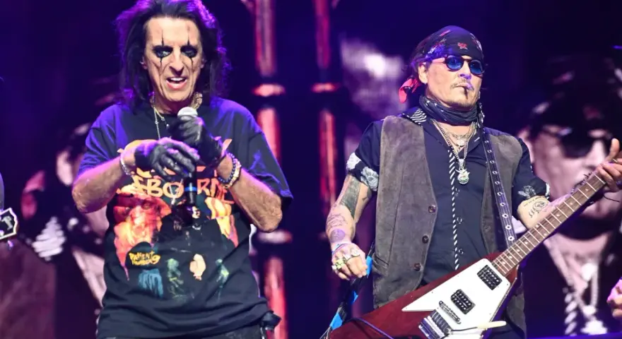 Alice Cooper i Johnny Depp, członkowie Hollywood Vampires, na scenie. Cooper śpiewa, Depp gra na gitarze.