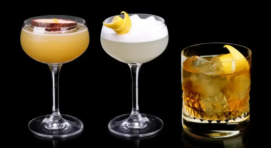 Trzy drinki: jeden z marakują, drugi z pianką i skórką cytryny, trzeci z lodem i skórką cytryny, każdy z nutą Cointreau.