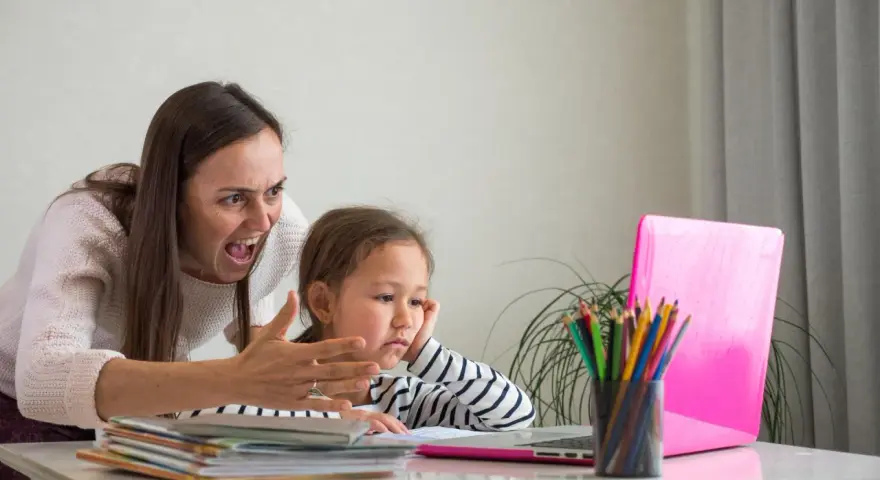 Zła kobieta krzyczy na dziecko przy laptopie.