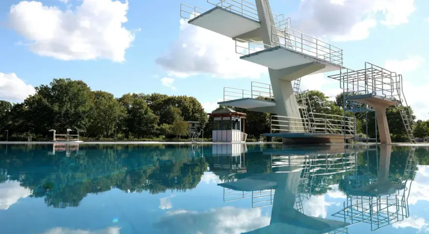 Sprungturm im Schwimmbad Pankow spiegelt sich im klaren Wasser. Ein sonniger Tag lädt zum Sprung ein.