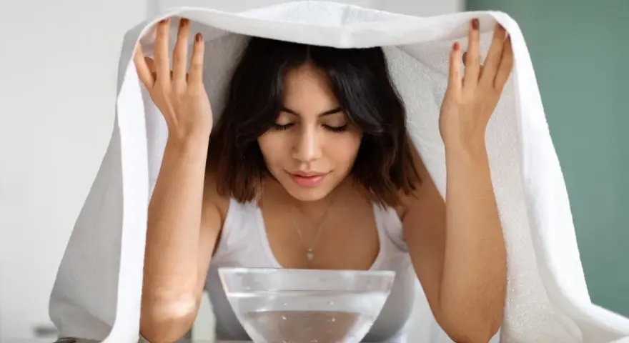 Eine Frau genießt ein Dampfbad für das Gesicht, um ihre Haut zu reinigen und zu revitalisieren.