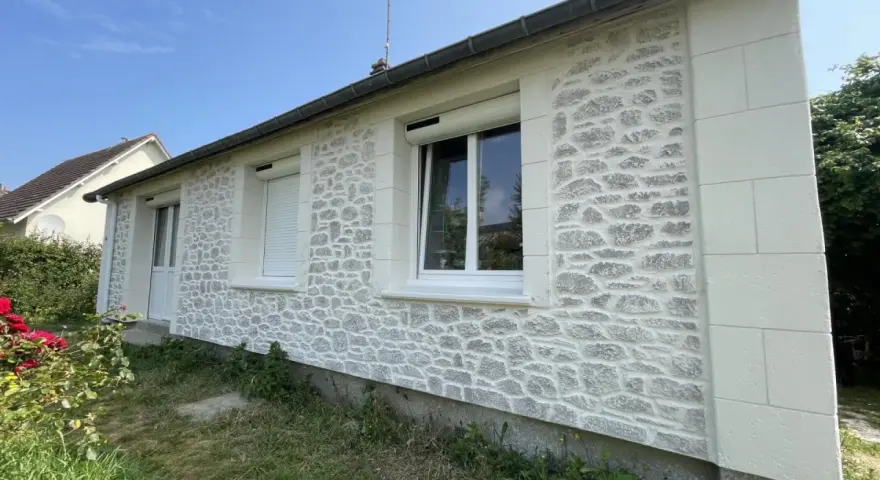 Façade de maison rénovée avec un enduit à la chaux imitant la pierre. Belle utilisation de la chaux pour un aspect authentique.