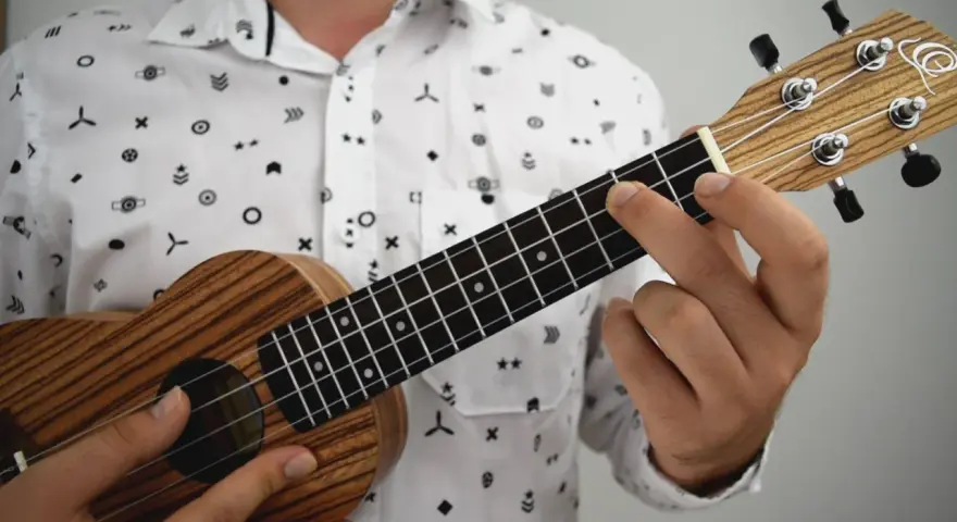 Dłoń dociska struny ukulele, tworząc akord. To jak czytanie tabulatury na gitarze, tylko na mniejszym instrumencie.