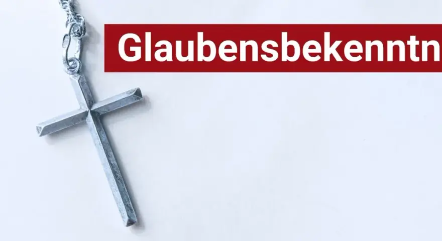 Ein silbernes Kreuz liegt neben dem Schriftzug "Glaubensbekenntnis".